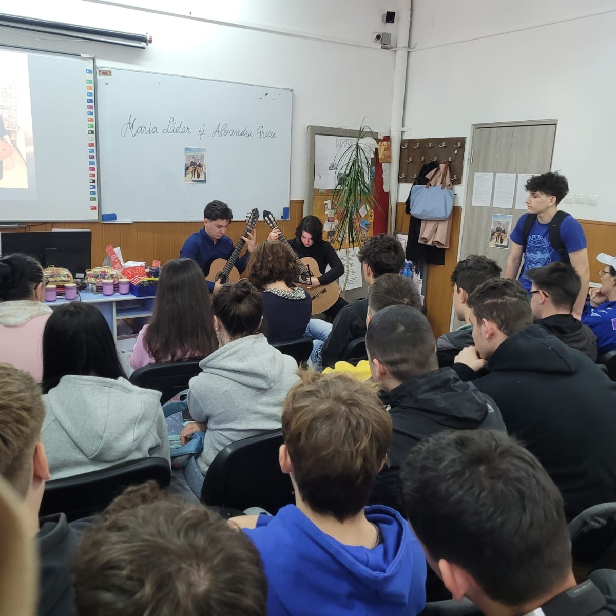 Publicul de elevi ascultă muzica de chitară